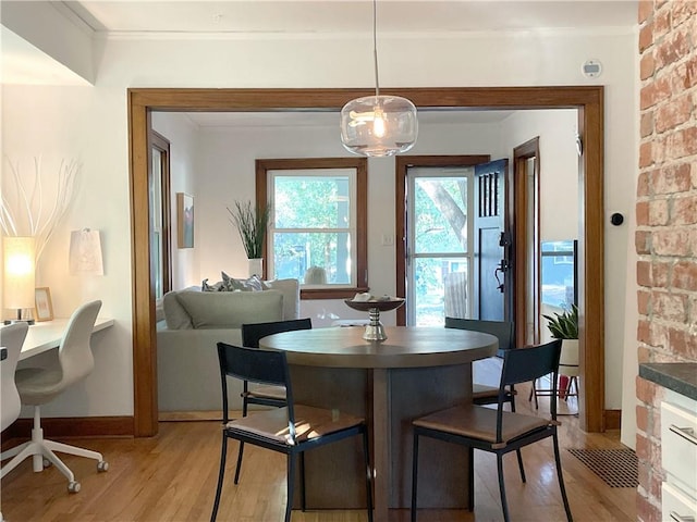 dining space with light wood finished floors, baseboards, and ornamental molding