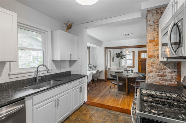 7235 Main St, Kansas City, MO 64114 - kitchen with stainless steel appliances, healthy amount of natural light, white cabinets, and dark stone counters