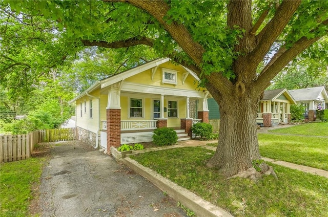 7235 Main St, Kansas City, MO 64114 - view of front facade with covered porch, brick siding, and asphalt driveway