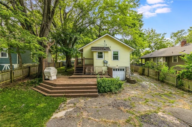 7235 Main St, Kansas City, MO 64114 - rear view of property featuring a deck, an attached garage, a fenced backyard, and driveway