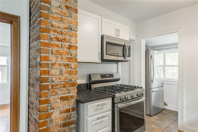 7235 Main St, Kansas City, MO 64114 - kitchen with stainless steel appliances, white cabinetry, dark countertops, and backsplash