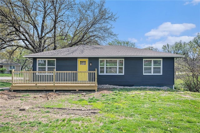 view of front facade featuring roof with shingles, a front yard, and a wooden deck