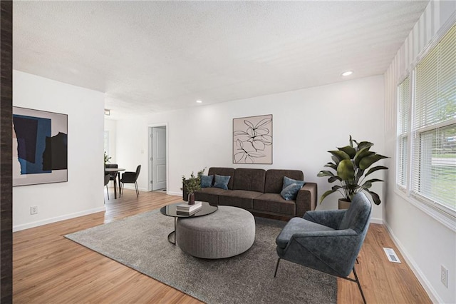 living area featuring baseboards, visible vents, light wood finished floors, and recessed lighting