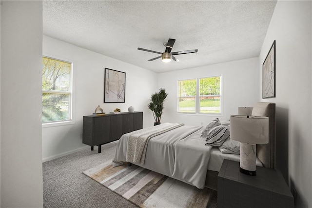 carpeted bedroom featuring a textured ceiling, multiple windows, ceiling fan, and baseboards