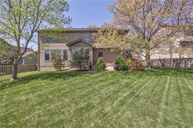 rear view of property featuring fence and a yard