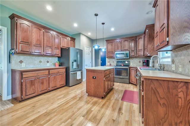 kitchen with appliances with stainless steel finishes, a center island, a sink, light countertops, and light wood finished floors