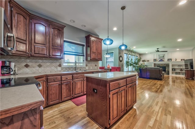 kitchen featuring a kitchen island, light wood-style floors, stainless steel microwave, a sink, and backsplash