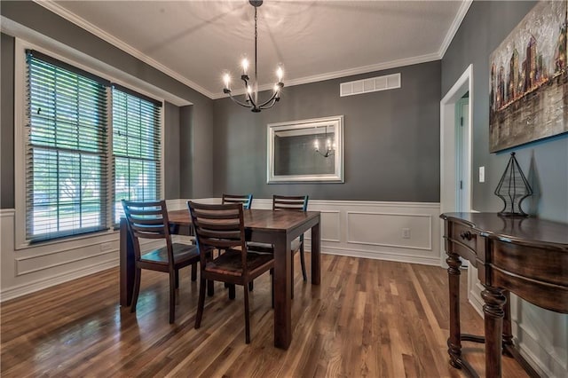 dining room with crown molding, a notable chandelier, wainscoting, dark wood-type flooring, and visible vents