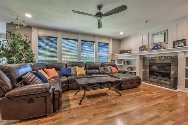 living area with ceiling fan, a textured ceiling, recessed lighting, wood finished floors, and a tile fireplace