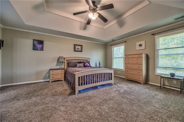 carpeted bedroom featuring crown molding, a ceiling fan, baseboards, a tray ceiling, and visible vents
