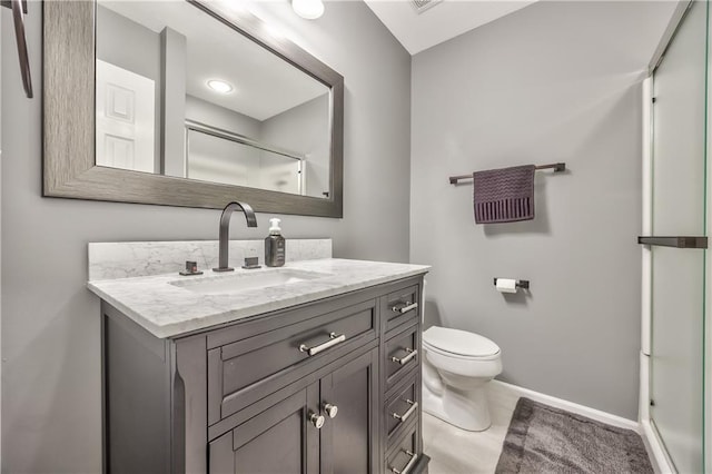 full bathroom with vanity, baseboards, a shower with shower door, and toilet