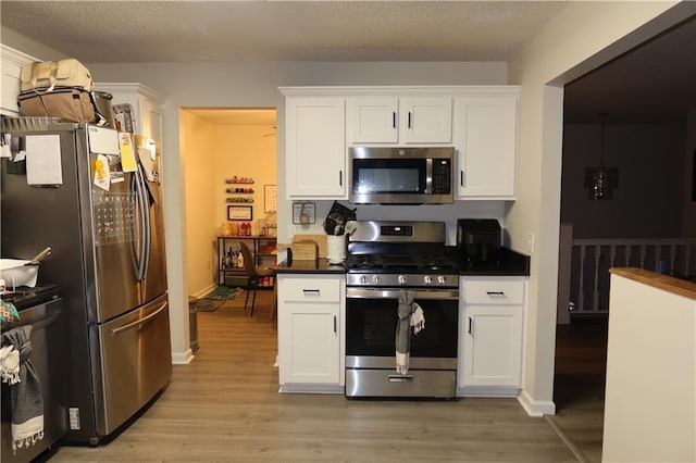 614 SE 145th Rd, Warrensburg, MO 64093 - kitchen featuring light wood finished floors, white cabinetry, dark countertops, and appliances with stainless steel finishes