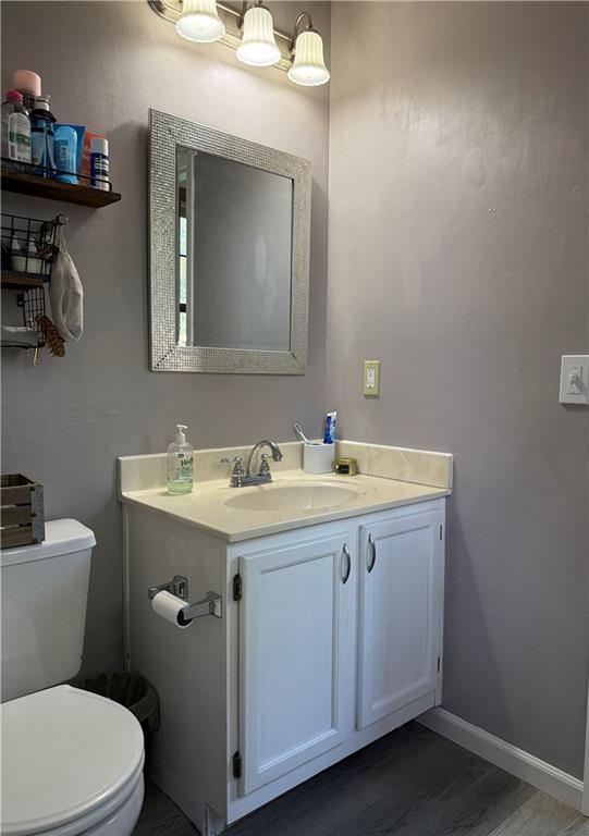 614 SE 145th Rd, Warrensburg, MO 64093 - bathroom with toilet, baseboards, vanity, and wood finished floors