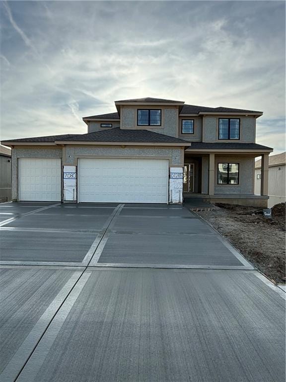 prairie-style home with concrete driveway, stucco siding, and a garage