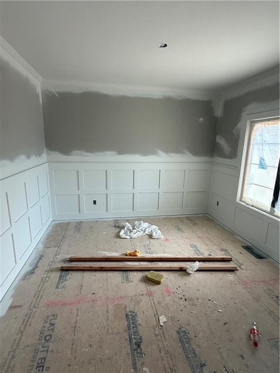 spare room with a wainscoted wall, visible vents, and a decorative wall