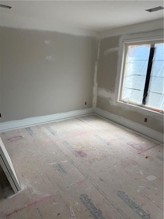 unfurnished room with baseboards