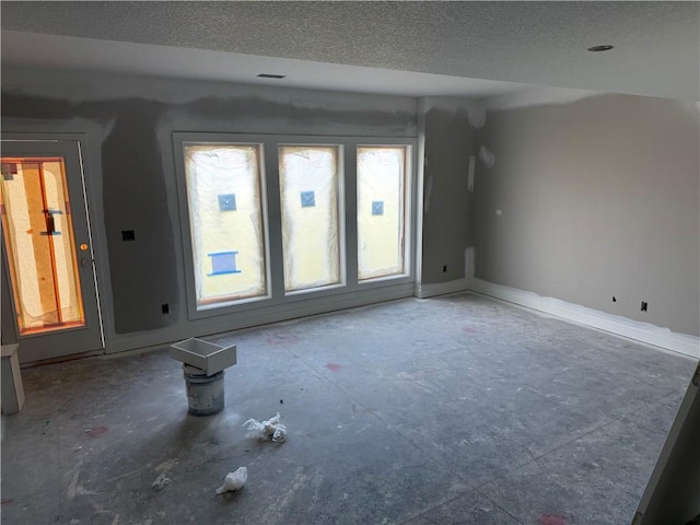 unfurnished room featuring a textured ceiling and baseboards