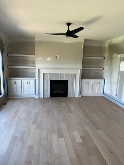 7080 NW Forest Lakes Dr, Parkville, MO 64152 - unfurnished living room featuring light wood finished floors, ceiling fan, and a fireplace
