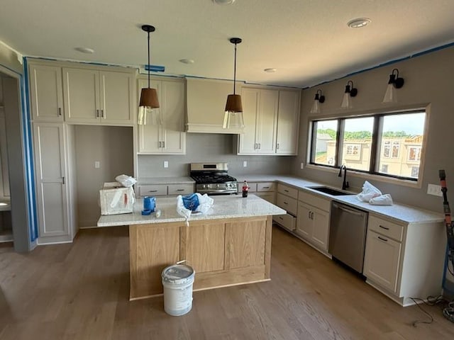 7080 NW Forest Lakes Dr, Parkville, MO 64152 - kitchen featuring appliances with stainless steel finishes, light wood-style flooring, a kitchen island, a sink, and hanging light fixtures