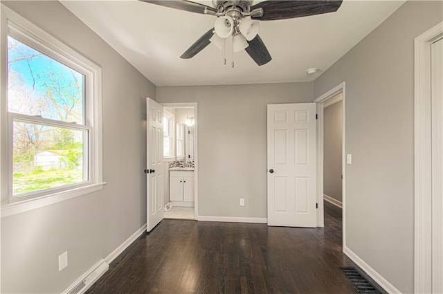 3422 N 71st St, Kansas City, KS 66109 - unfurnished bedroom with dark wood-style floors, baseboards, visible vents, baseboard heating, and ensuite bath