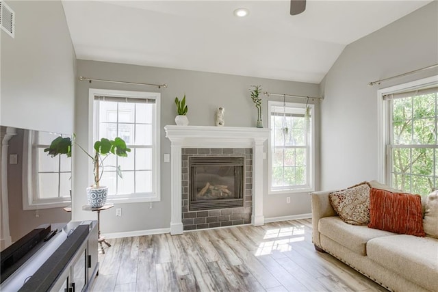 living room with vaulted ceiling, a wealth of natural light, and light wood-style floors