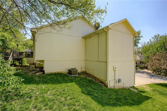 view of side of home featuring central air condition unit, a deck, and a lawn