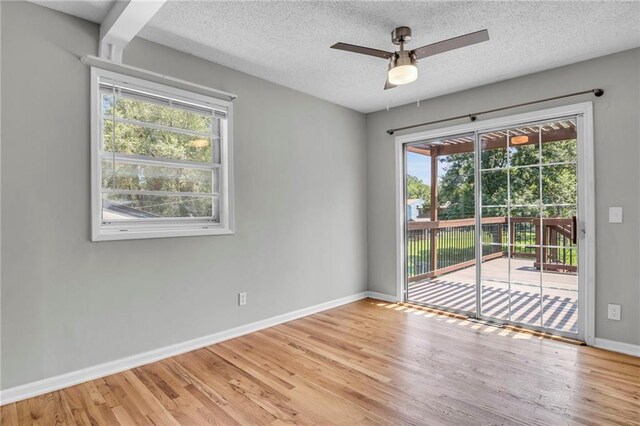 empty room with plenty of natural light, light wood-type flooring, baseboards, a textured ceiling, and a ceiling fan