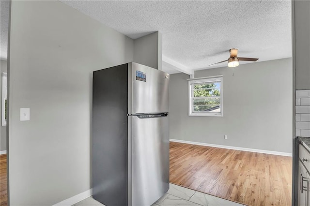 kitchen with freestanding refrigerator, a textured ceiling, a ceiling fan, and baseboards