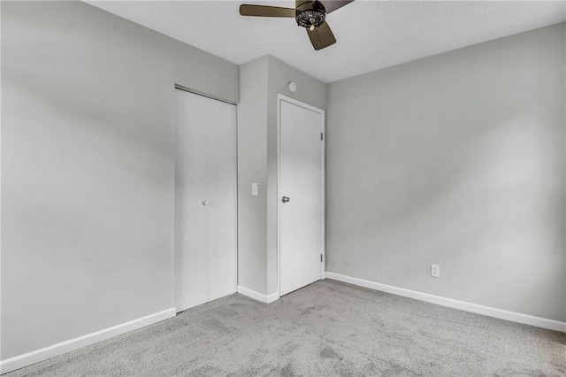 unfurnished bedroom featuring carpet flooring, baseboards, a closet, and a ceiling fan