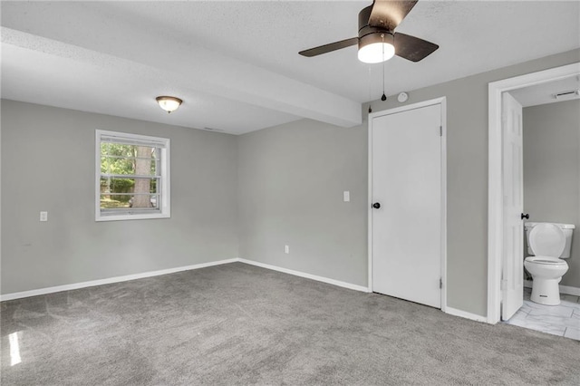 unfurnished bedroom featuring carpet flooring, baseboards, ensuite bath, and a textured ceiling