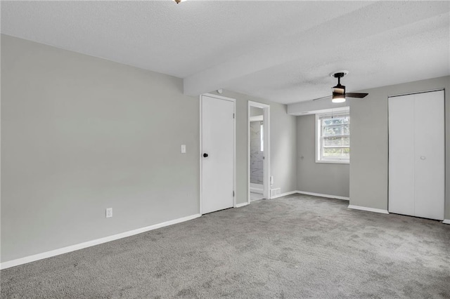 unfurnished bedroom with a textured ceiling, carpet, baseboards, connected bathroom, and a ceiling fan