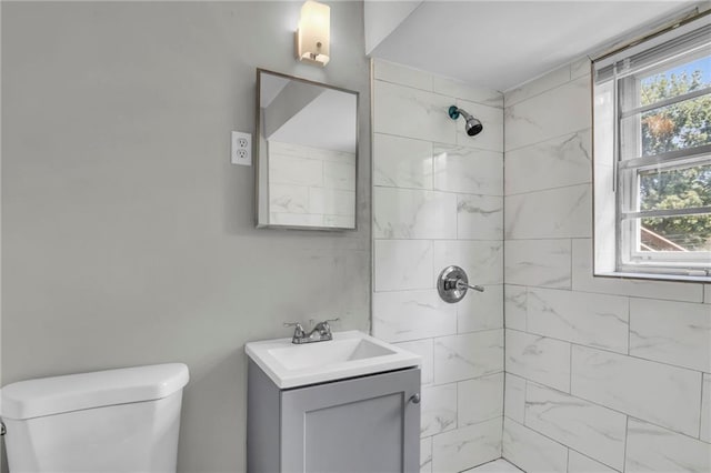 full bath with tiled shower, vanity, and toilet