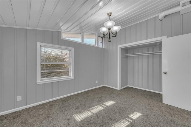 unfurnished bedroom featuring an inviting chandelier, visible vents, carpet floors, and a closet