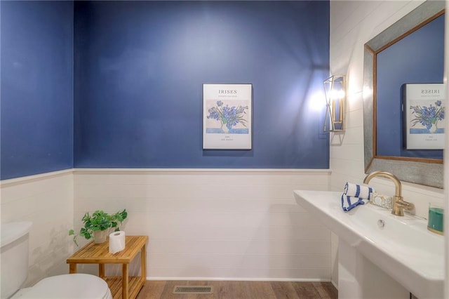 8120 Lone Elm Rd, Lenexa, KS 66220 - bathroom featuring toilet, tile walls, a sink, wood finished floors, and wainscoting