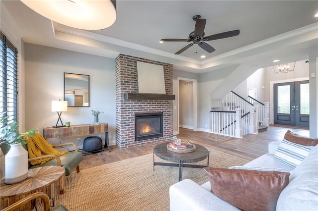 8120 Lone Elm Rd, Lenexa, KS 66220 - living area with a tray ceiling, wood finished floors, a fireplace, crown molding, and stairway