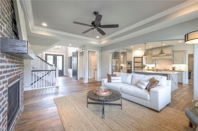 8120 Lone Elm Rd, Lenexa, KS 66220 - living room featuring a fireplace, a tray ceiling, wood finished floors, ceiling fan, and arched walkways