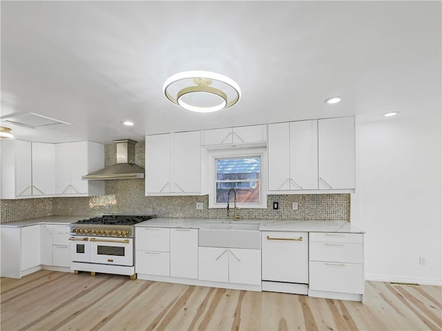 3214 S Hawthorne Ave, Independence, MO 64052 - kitchen featuring a sink, white cabinetry, range with two ovens, and wall chimney range hood