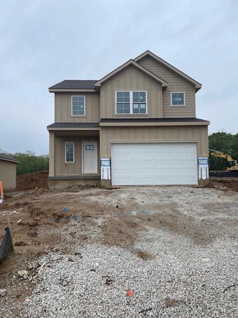 traditional-style home with gravel driveway, an attached garage, and board and batten siding