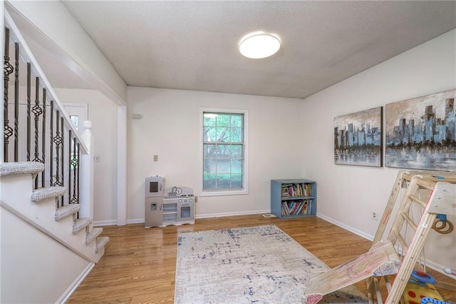 entrance foyer featuring stairway, wood finished floors, a textured ceiling, and baseboards