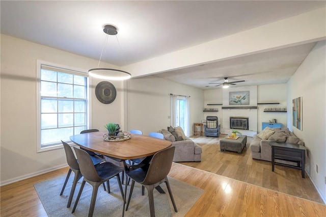 dining room with healthy amount of natural light, baseboards, wood finished floors, and a fireplace