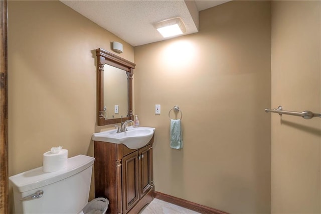 bathroom featuring vanity, toilet, a textured ceiling, and baseboards