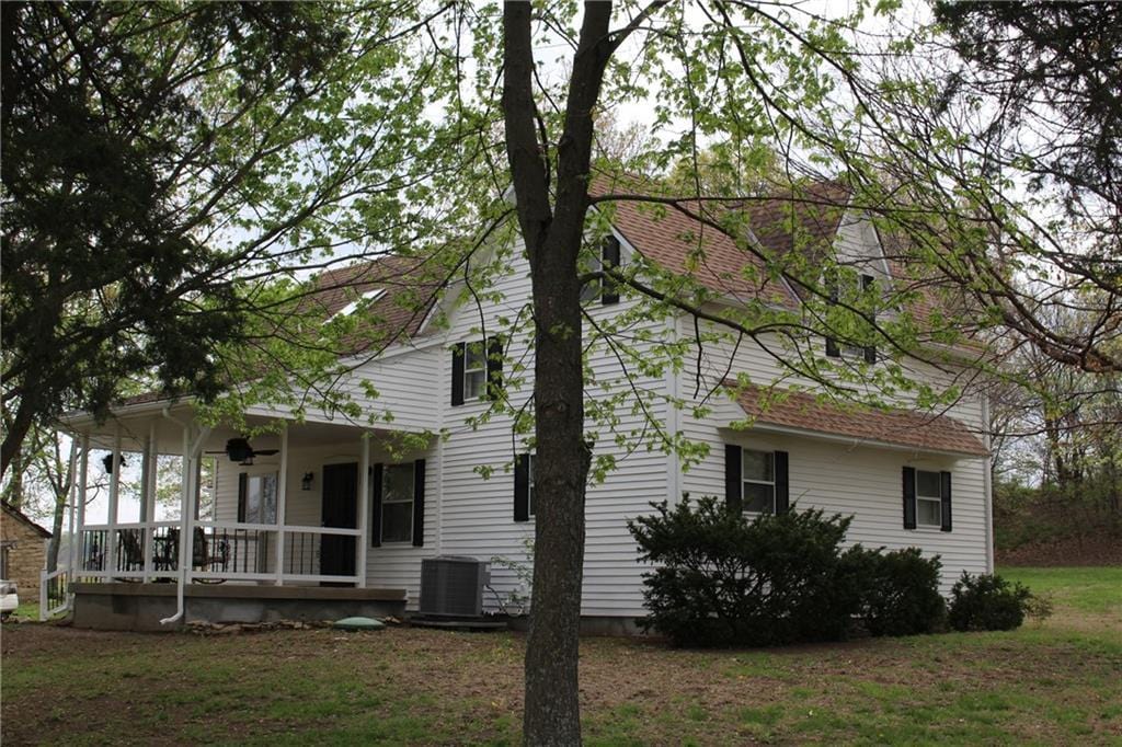 view of side of home with central AC, a porch, and a lawn