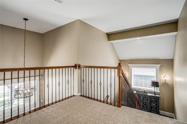 corridor with carpet floors, baseboards, and vaulted ceiling