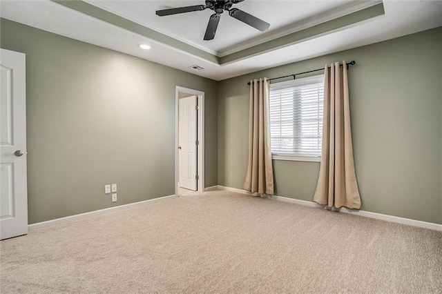 carpeted spare room with crown molding, baseboards, ceiling fan, recessed lighting, and a raised ceiling