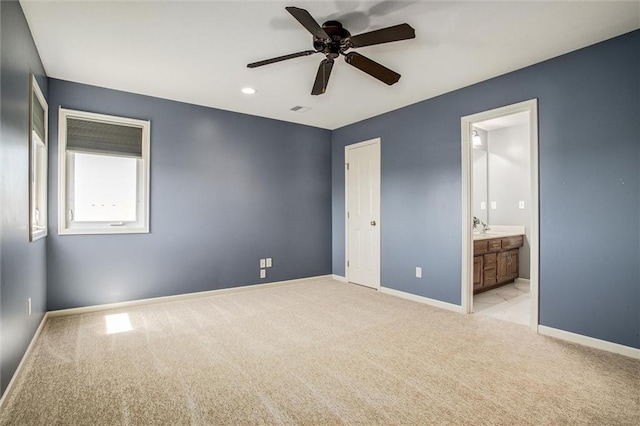 unfurnished bedroom with ceiling fan, light colored carpet, ensuite bath, baseboards, and visible vents