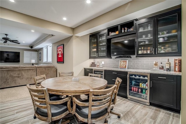 bar featuring indoor wet bar, beverage cooler, light wood-type flooring, and tasteful backsplash