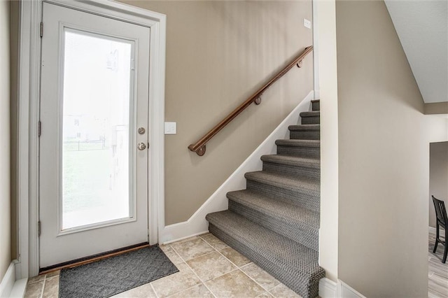 foyer featuring baseboards, a healthy amount of sunlight, and stairway
