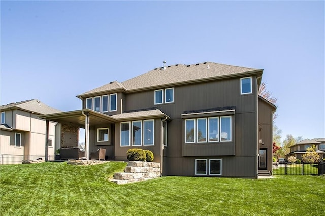 back of property featuring a lawn, roof with shingles, and fence