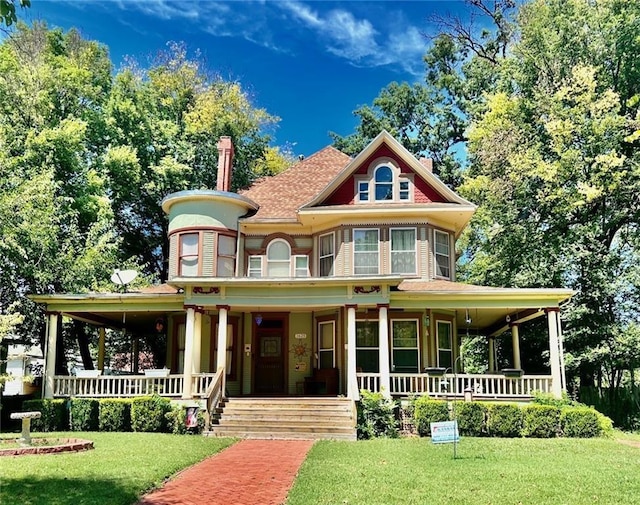 victorian-style house with a front lawn, a porch, and roof with shingles