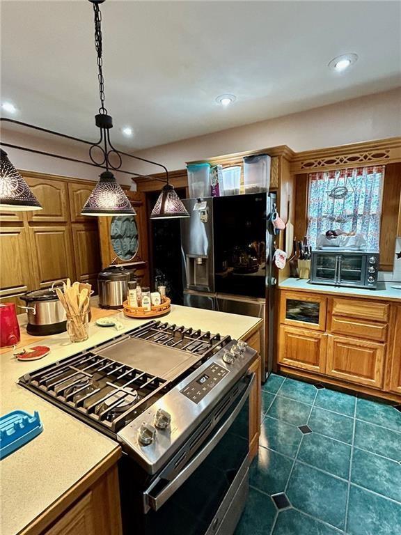kitchen with stainless steel gas stove, light countertops, brown cabinets, and recessed lighting